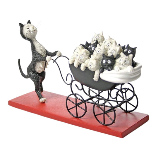A whimsical figurine of a black-and-white cat pushing a black metal baby stroller filled with small white and black kittens, mounted on a rectangular red base against a plain white background.